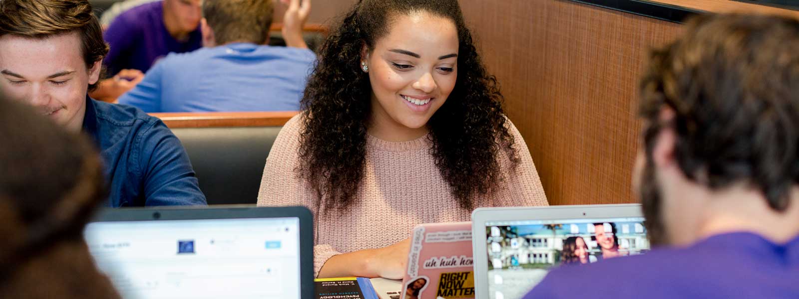 students smiling while sitting in desks in a circle in classroom