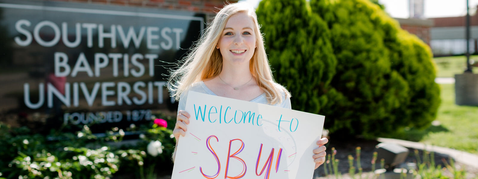 male student and female student pose outside building