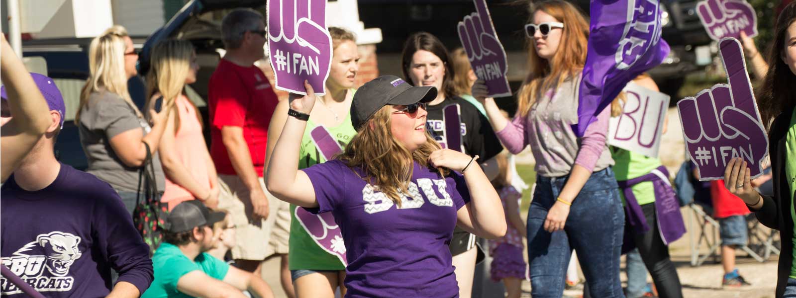 students with foam fingers marching in Homecoming parade