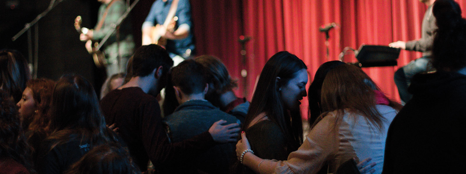 three guitarists and drummer leading worship in chapel service