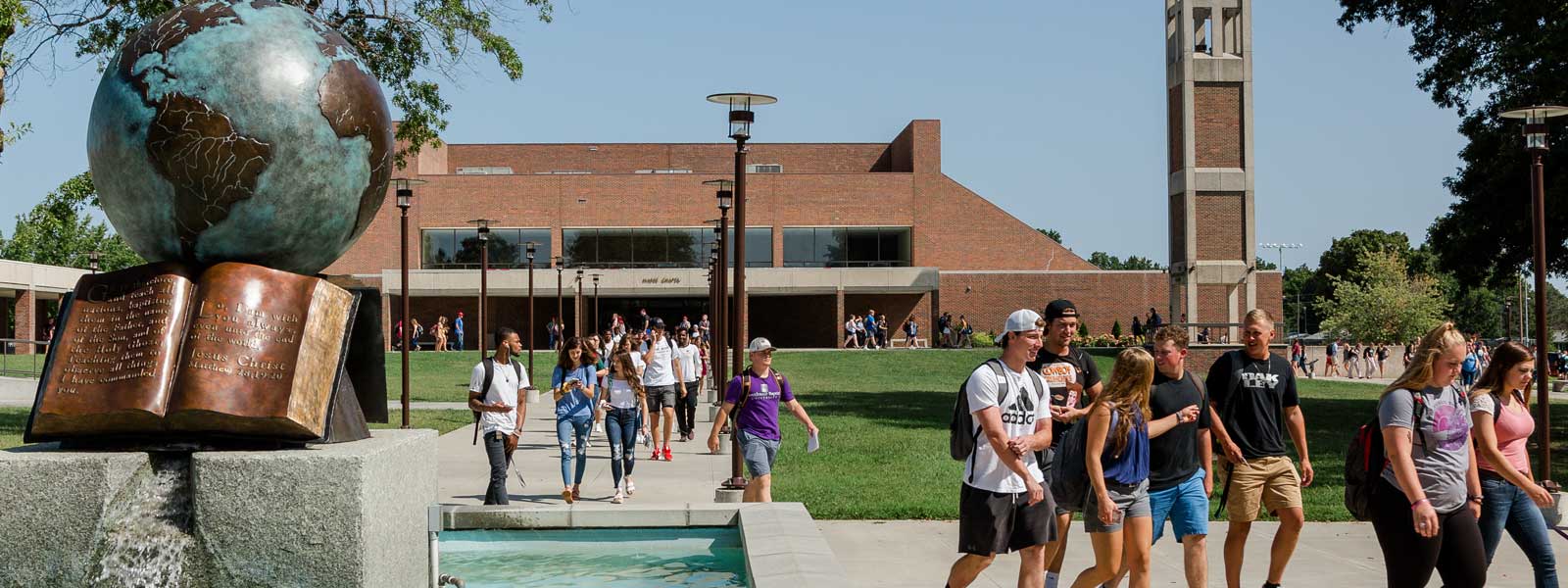 view of globe sculpture fountain as students walk out of chapel