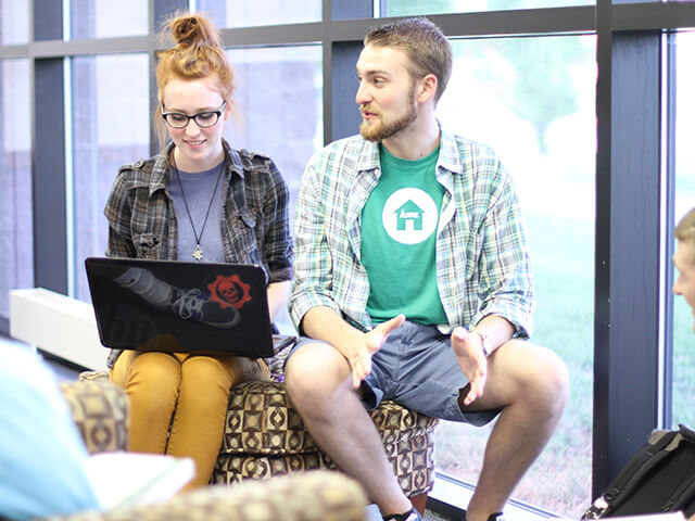 two students working together in library with laptop